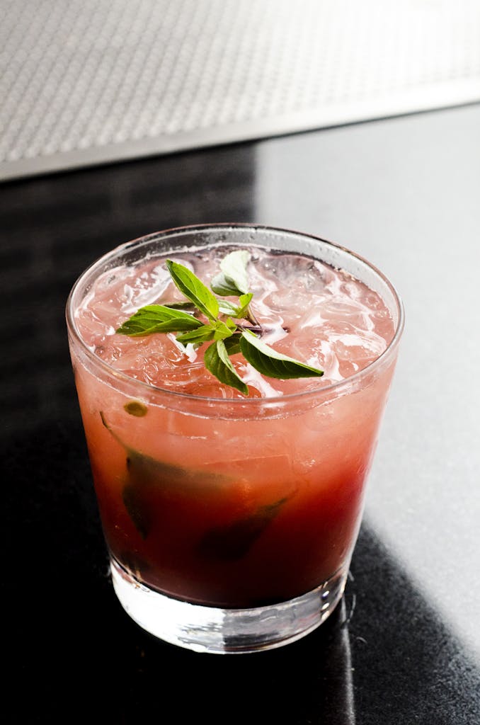 Delicious cold cocktail with mint garnish served in a glass on a bar counter. Perfect for summer refreshment.