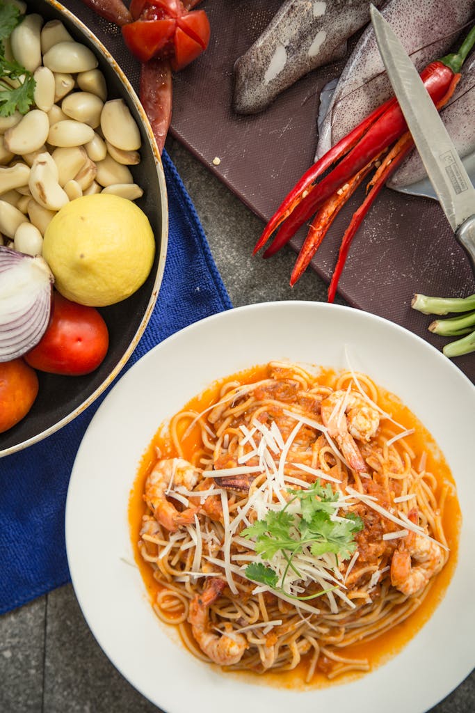 Mouth-watering shrimp pasta garnished with fresh herbs and accompanied by raw ingredients.