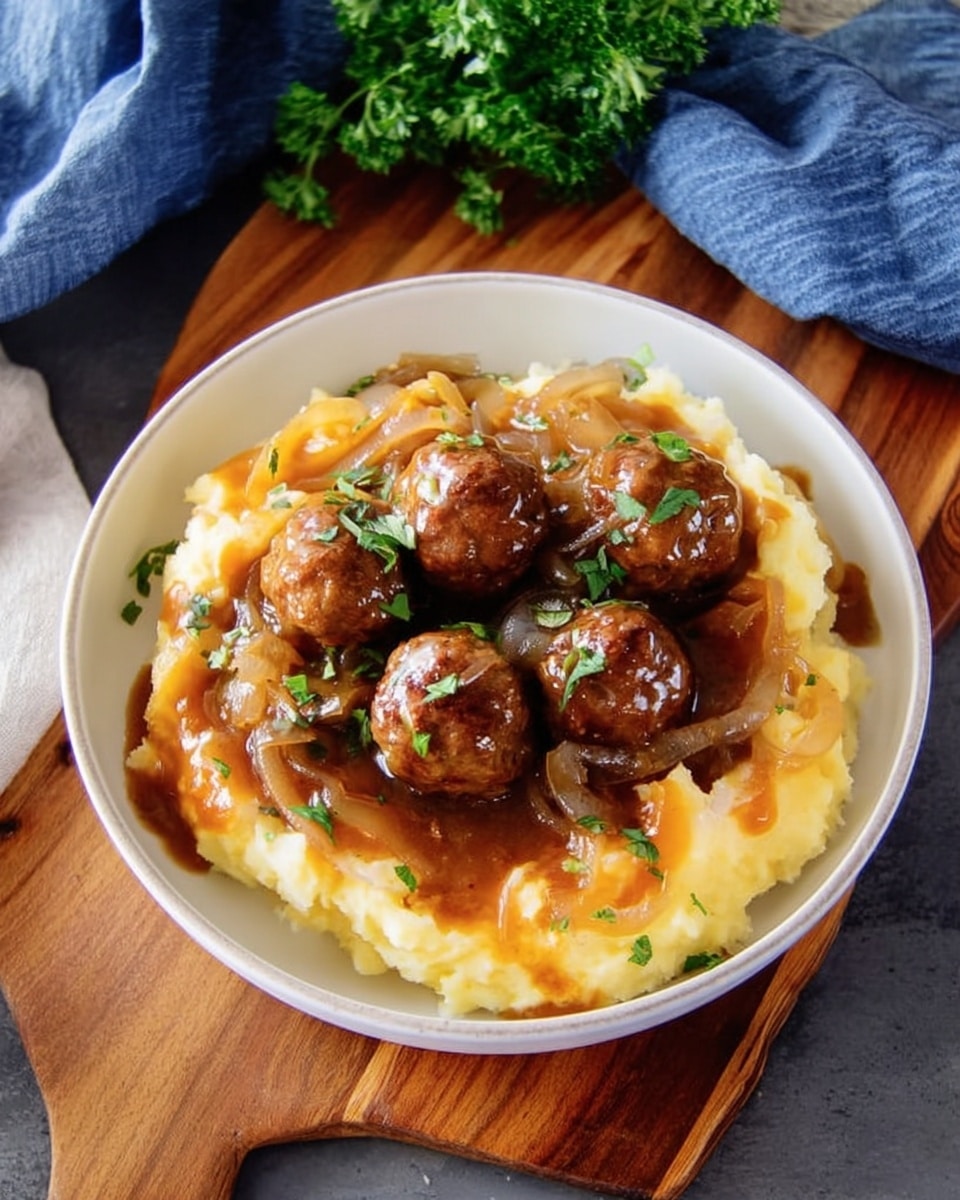 A white bowl holds a layered dish starting with creamy mashed potatoes at the bottom, pale yellow in color with a smooth texture. On top of this is a rich brown gravy with visible cooked onions that add a slight translucent and soft texture, spilling gently over the mashed potatoes. Resting on the gravy are several round, browned meatballs, slightly shiny from the sauce, giving a savory and juicy appearance. The dish is garnished with small green herbs sprinkled lightly over the meatballs and sauce. The bowl sits on a wooden board, next to a blue cloth napkin and some fresh parsley. Photo taken with an iphone --ar 4:5 --v 7