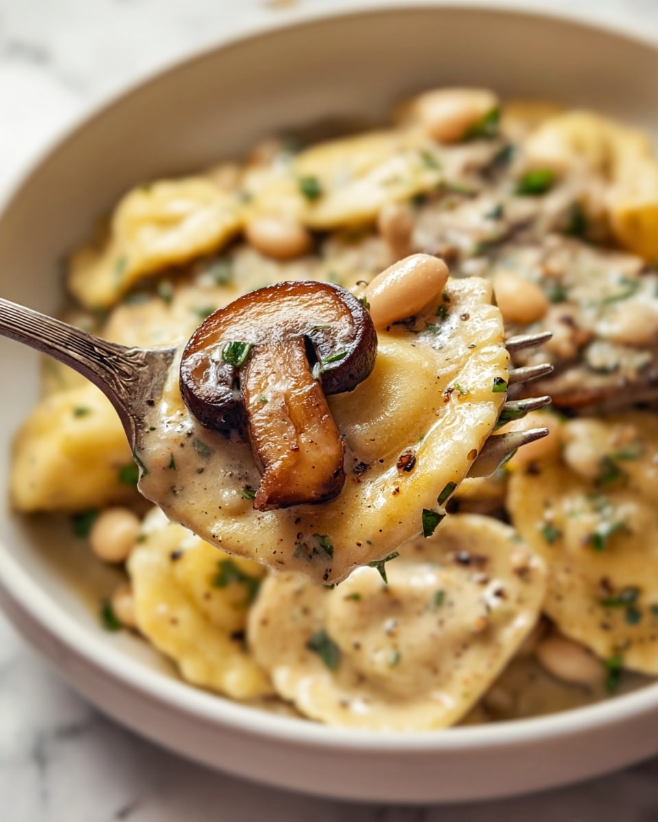 A close-up of a fork holding a bite of creamy pasta with three main layers: the top layer is a cooked mushroom slice with a brown and slightly shiny texture; beneath it, smooth, light beige creamy sauce covers soft white beans; the bottom layer consists of tender ravioli pasta pieces in a pale yellow color, all speckled with small green herb bits and black pepper flecks. The background shows a white bowl filled with the same creamy pasta dish on a white marbled surface. Photo taken with an iphone --ar 4:5 --v 7