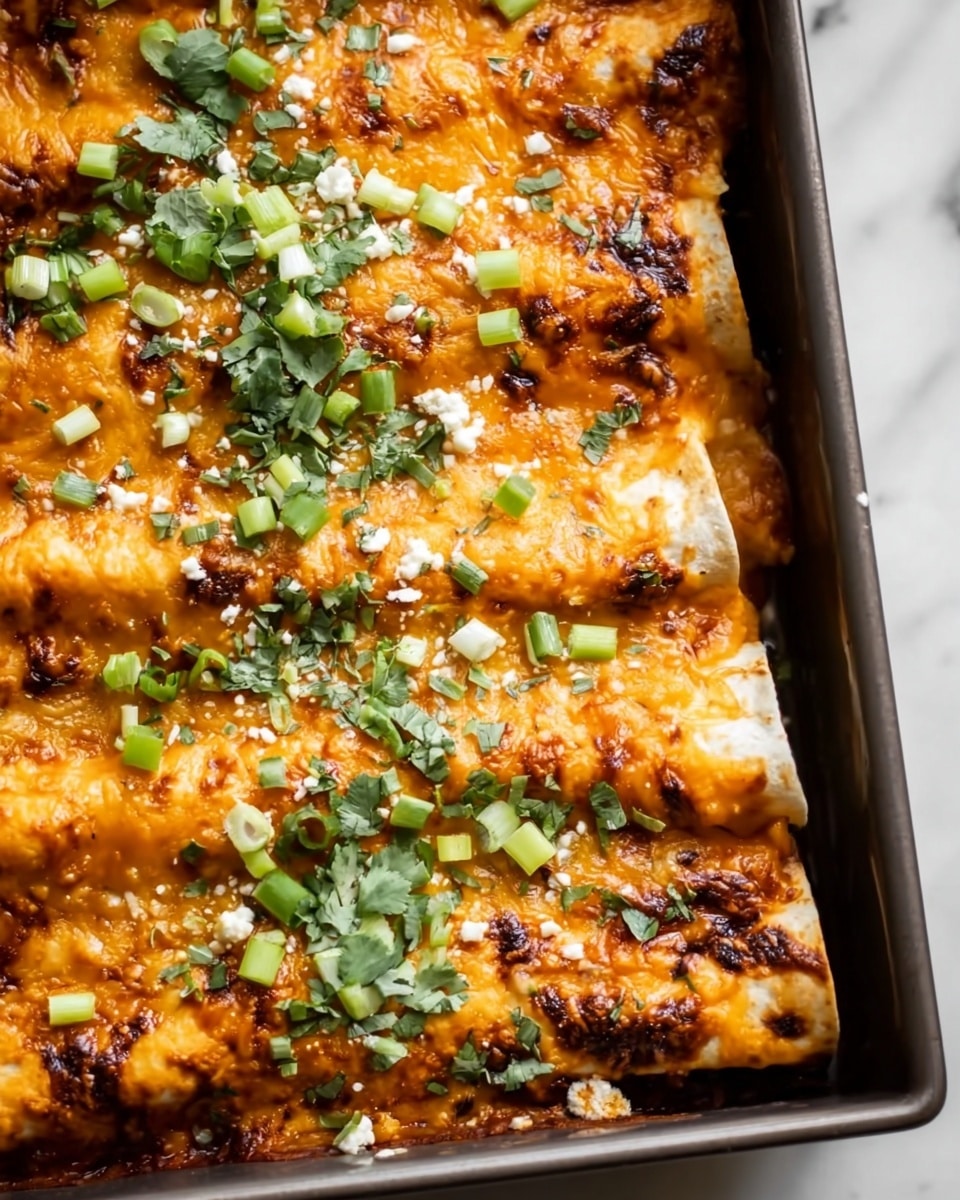 The image shows a close-up of a baked dish with several rolled layers of white tortillas filled with a rich, melted orange cheese sauce. The top layer is golden brown with some darker, slightly burnt spots, and is covered with small, bright green chopped herbs and scallions scattered evenly. Tiny bits of white cheese crumbs are sprinkled on top, adding texture and color contrast. The dish is presented in a dark baking tray sitting on a white marbled surface. photo taken with an iphone --ar 4:5 --v 7