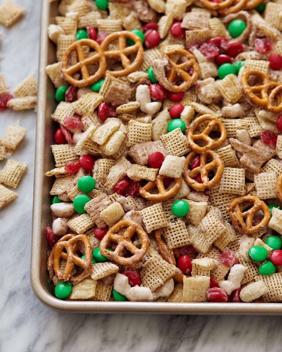 The image shows a close-up of a snack mix on a baking tray, featuring multiple layers of different ingredients all mixed together. The base layer includes light tan Chex cereal squares with a slightly rough texture, beige round Cheerios, and small twisted pretzels in a light brown color with a crunchy look. Scattered among these are small red and green candy-coated chocolates, and some pieces appear to be covered in a shiny white coating, likely yogurt or white chocolate. The whole mixture sits on a white marbled surface that is visible around the edges of the tray. Photo taken with an iphone --ar 4:5 --v 7