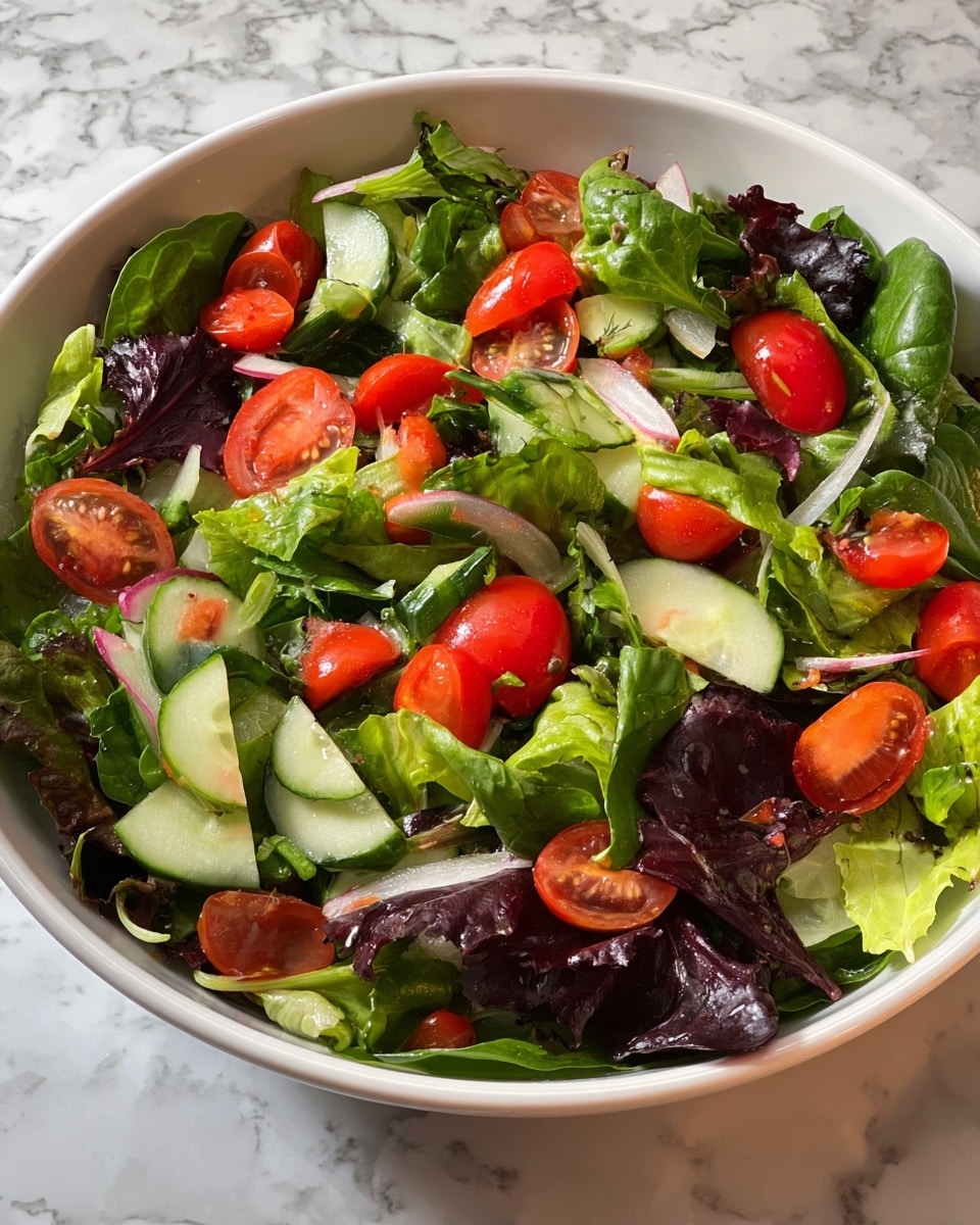 A white bowl filled with a fresh mixed salad sits on a white marbled texture. The salad has several layers: the base is made of various leafy greens including spinach and different lettuce types, showing vibrant green and dark purplish leaves. On top, fresh bright red grape tomatoes are scattered whole and halved, adding a juicy texture. Chopped cucumber pieces with their dark green skin and pale inside are spread evenly, along with thin slices of white onion adding a slight crunch. The salad looks lightly dressed, giving a glossy shine to the vegetables. photo taken with an iphone --ar 4:5 --v 7