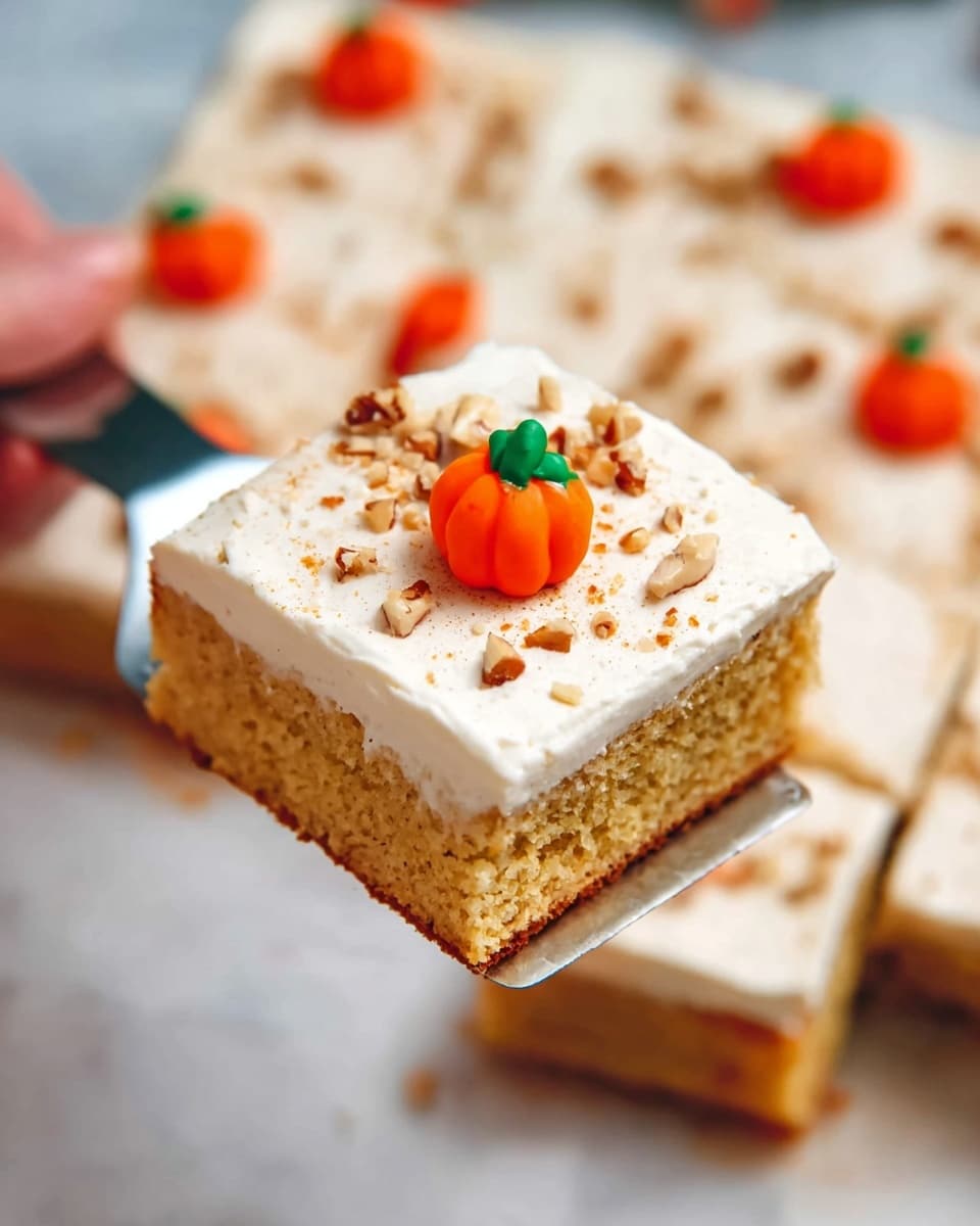 A square piece of cake is held by a woman's hand with a silver spatula. The cake has two layers: a dense golden-brown base and a thick smooth white frosting on top. The frosting is sprinkled with small chopped nuts and lightly dusted with a brown powder. In the center of the frosting, there is a small decorative orange candy pumpkin with a bright green stem. In the background, more pieces of the same cake can be seen arranged on a white marbled surface. The image is bright and clear, showing the soft texture of the cake and the creamy topping. Photo taken with an iphone --ar 4:5 --v 7
