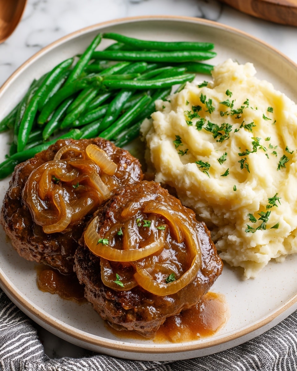 The dish shows two thick brown beef patties covered with a shiny brown onion gravy that has sliced soft onions on top, placed on the bottom right of a round white plate. Next to the patties, on the top right, is a heap of creamy mashed potatoes with a smooth, slightly fluffy texture, garnished with small bits of chopped green herbs. To the left of both the patties and mashed potatoes is a neat pile of long, vibrant green cooked green beans that look tender but still crisp. The plate sits on a white marbled surface with part of a gray-striped cloth underneath the plate's right side. photo taken with an iphone --ar 4:5 --v 7
