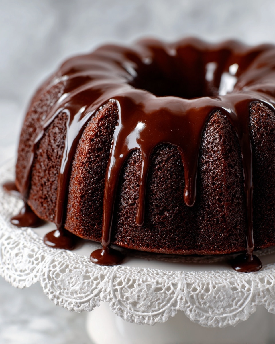 A rich, dark chocolate bundt cake with a moist texture sits on a white cake stand with a delicate lace-like pattern. The cake has deep ridges from the bundt mold, and a glossy, thick chocolate glaze is slowly dripping down the sides in thick streams, pooling slightly at the base. The background is a soft, white marbled texture that makes the dark cake and shiny glaze stand out clearly. photo taken with an iphone --ar 4:5 --v 7