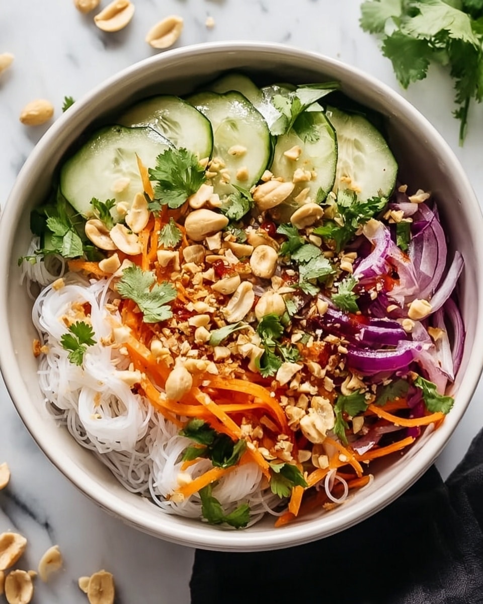 This image shows a bowl with several layers of colorful fresh salad ingredients. The base layer is thin white rice noodles. On top of this, there are slices of light green cucumber arranged around the edges. There are orange carrot strips and slices of purple onion spread across the bowl. Crushed light brown peanuts are sprinkled all over, along with fresh green cilantro leaves. The bowl itself is white with a smooth finish, placed on a white marbled surface with a few scattered peanuts nearby. Photo taken with an iphone --ar 4:5 --v 7