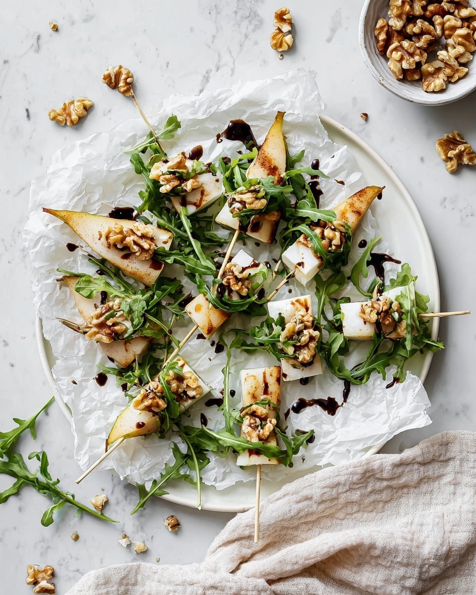 The image shows a round white plate lined with crumpled white parchment paper, holding nine small skewers arranged in a loose circle. Each skewer has three layers: a toasted light brown triangular pear piece on the bottom, a small bunch of fresh green arugula leaves in the middle, and a white wedge of soft cheese topped with a small pile of brown walnut pieces on top. Dark balsamic glaze droplets are drizzled on the cheese and scattered around on the parchment. Around the plate, loose arugula leaves and walnut pieces are visible along with a small white bowl of walnuts in the top right corner and a putty textured white cloth at the bottom right corner, all on a white marbled surface. Photo taken with an iphone --ar 4:5 --v 7