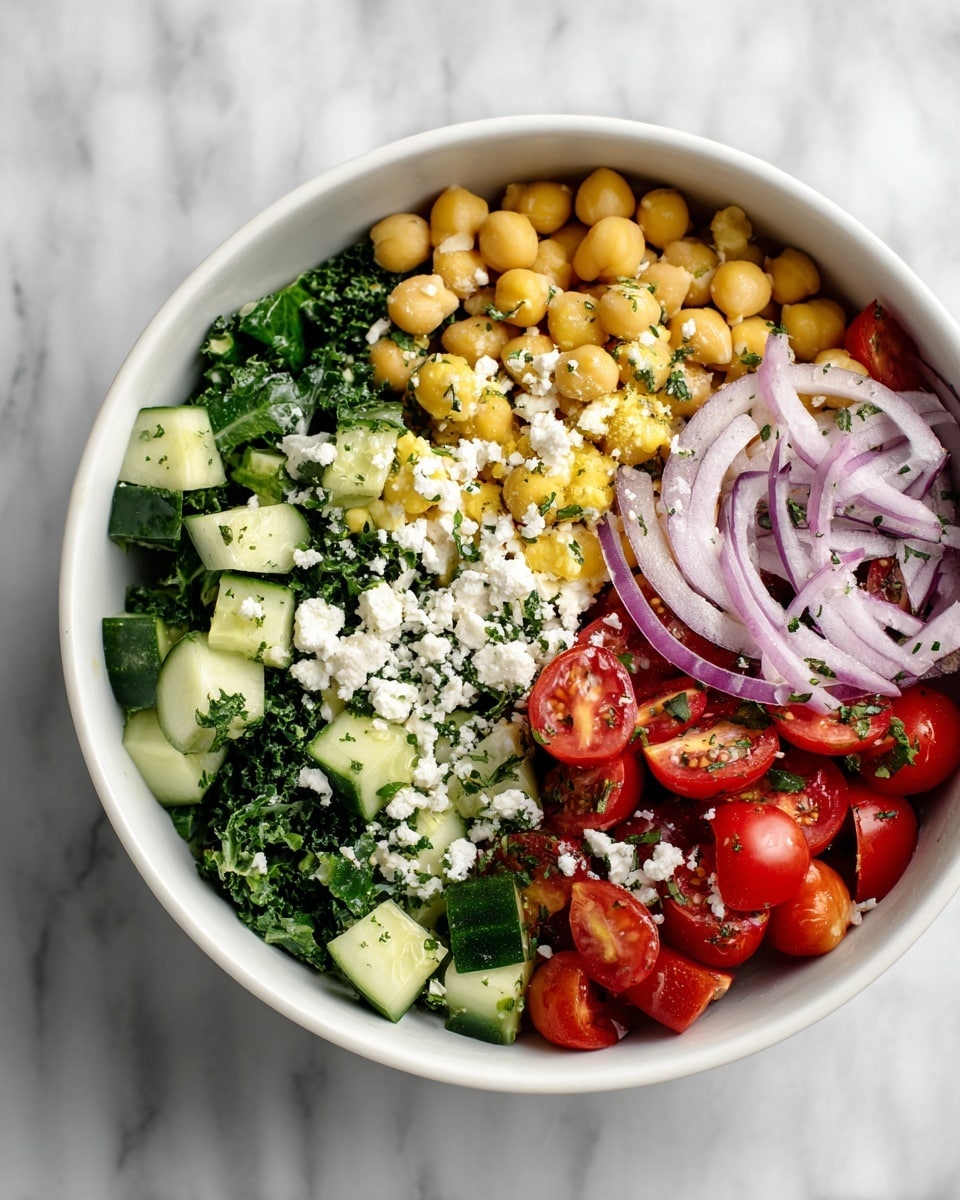 A close-up of a bowl of chickpea salad with about four main layers: at the bottom, roughly chopped green leafy herbs; on top of that, diced green cucumbers scattered evenly; next, several small bright red cherry tomato halves and whole tomatoes spread around; dotted throughout are many round beige chickpeas. White chunks of soft feta cheese are placed mostly in the center, some slightly cracked with black pepper sprinkled on them. A few thin slices of purple onion rest near the edge of the white bowl, which sits on a white marbled surface. The photo taken with an iphone --ar 4:5 --v 7