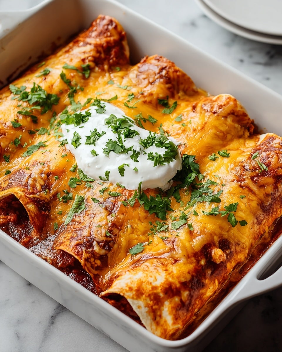 The image shows three rolled enchiladas placed side by side in a white rectangular baking dish. The enchiladas are covered with a layer of melted, golden-yellow cheese that has lightly browned spots, mixed with a reddish-brown sauce that seeps around the edges. A dollop of white sour cream sits on top in the middle, garnished with bright green chopped cilantro scattered across the cheese and sour cream. The background is a white marbled surface, adding a clean and fresh look to the presentation. photo taken with an iphone --ar 4:5 --v 7