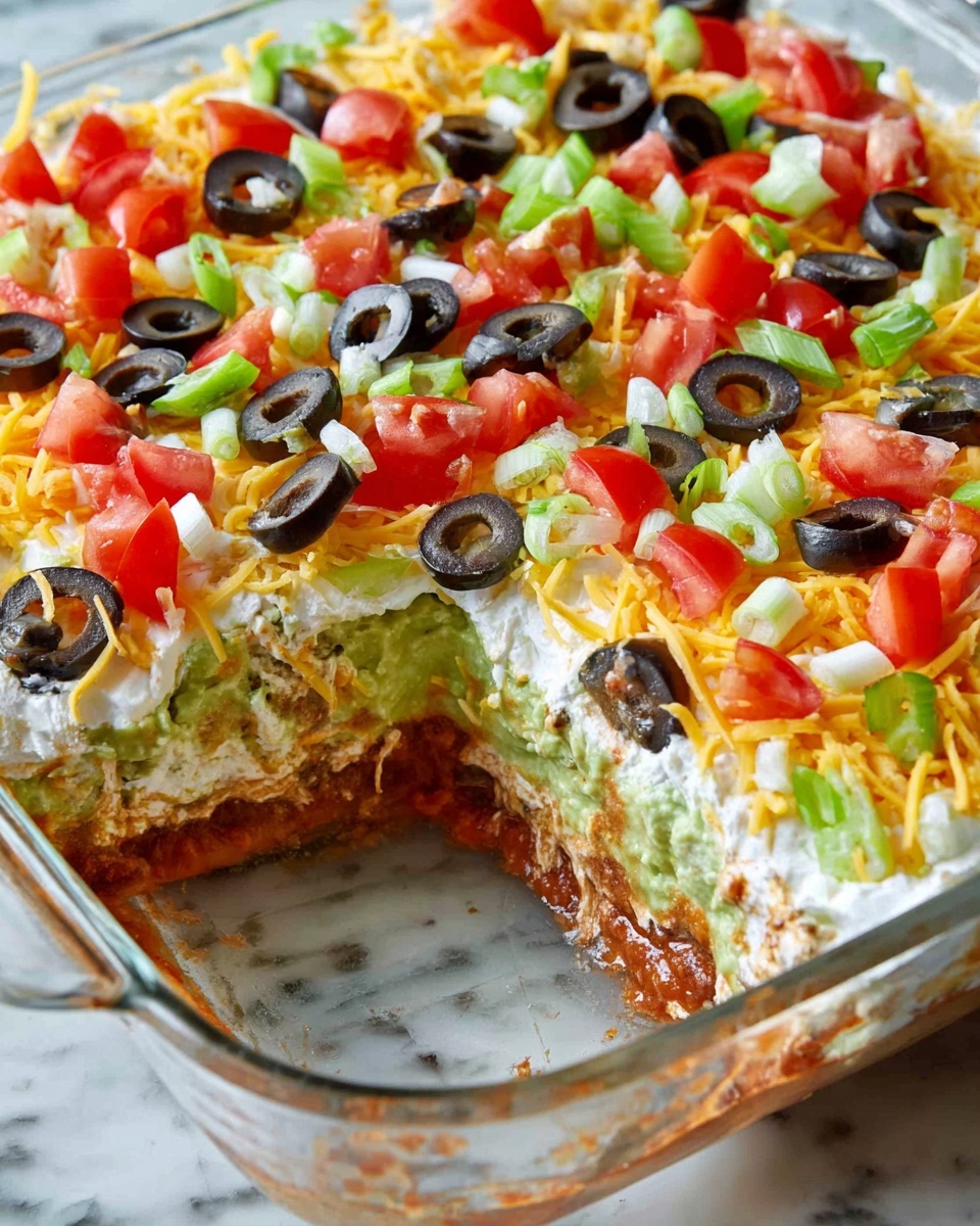 The image shows a layered dip in a clear glass square dish, with a portion missing from one corner, revealing multiple layers inside. The bottom layer looks reddish, possibly salsa or beans, followed by a light green layer that seems like guacamole. Above this is a white creamy layer, topped with shredded yellow and white cheese mixed together. The top layer is decorated with halved black olives, chopped red tomatoes, and small pieces of green onions, all scattered evenly. The dish is placed on a surface with a white marbled texture. photo taken with an iphone --ar 4:5 --v 7