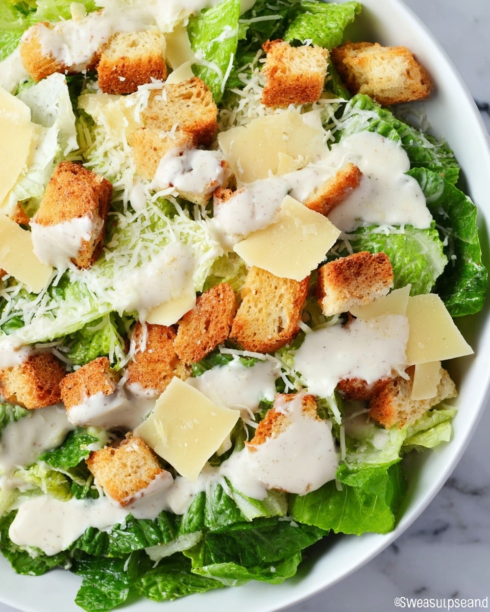 A close-up view of a Caesar salad arranged in a white bowl, showing three main layers: the bottom fresh green romaine lettuce leaves with a crisp texture, the middle layer of light yellow shaved Parmesan cheese slices scattered unevenly, and the top layer of golden brown crunchy croutons spread over the lettuce. All layers are generously drizzled with creamy white Caesar dressing that pools slightly on the cheese and croutons. The bowl rests on a white marbled surface, highlighting the fresh and appetizing colors and textures. photo taken with an iphone --ar 4:5 --v 7