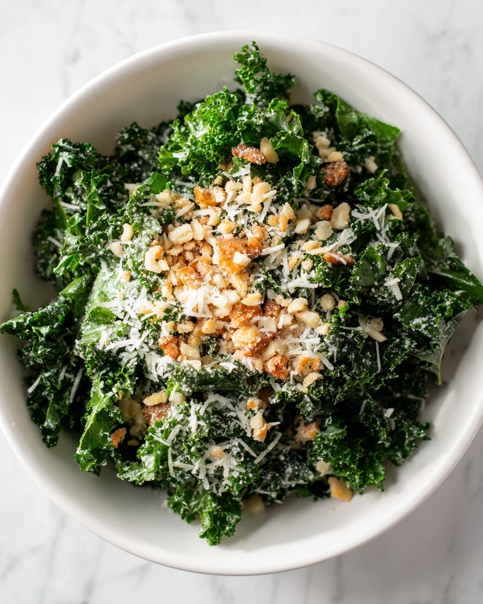 A white bowl filled with a fresh kale salad, the kale leaves are dark green, curly, and fresh-looking, forming the main layer. On top of the kale, there is a layer of small, light brown crunchy pieces, possibly toasted breadcrumbs or nuts, adding texture. The salad is lightly sprinkled with finely grated pale white cheese, adding a fine, powdery texture scattered evenly across the surface. The bowl sits on a white marbled table which adds a clean, bright background to the image. photo taken with an iphone --ar 4:5 --v 7