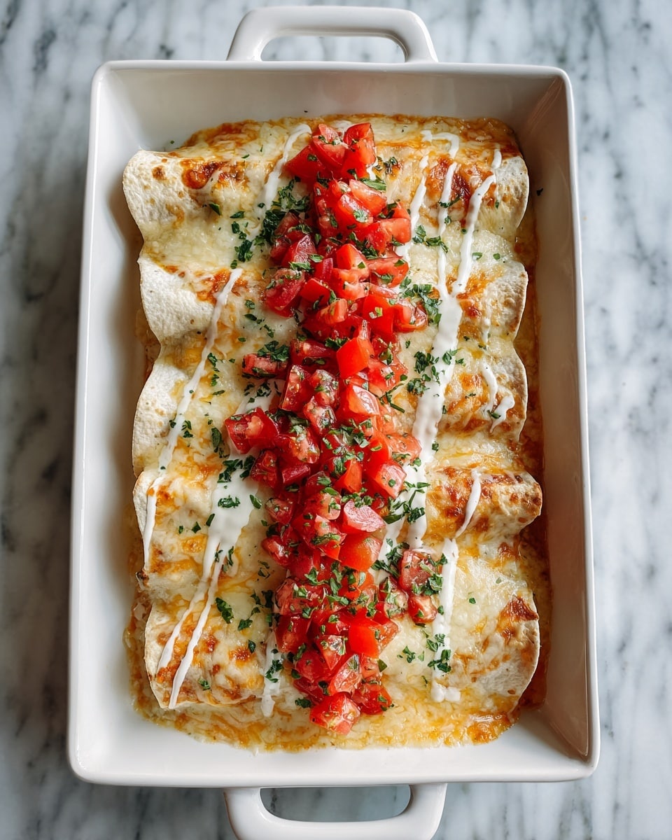 A white rectangular dish holds three rolled enchiladas side by side, each covered with a layer of melted orange and white cheese mixed with creamy white sauce drizzled in stripes on top. Freshly chopped red tomatoes are piled along the center, and small green herbs are sprinkled over the cheese and tomatoes. The dish sits on a white marbled surface. photo taken with an iphone --ar 4:5 --v 7