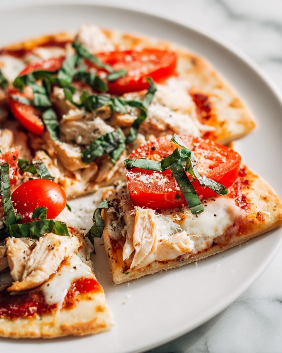 A round pizza with a thin light brown crust is placed on a white plate, sitting on a white marbled surface. The pizza is cut into eight slices and layered with a spread of red tomato sauce under soft white melted cheese. On top, there are uneven pieces of grilled golden-brown chicken, fresh red tomato wedges, and thin strips of bright green basil scattered all over. A light sprinkle of grated cheese and black pepper adds texture and contrast on the colorful toppings. The close-up shows a fresh, vibrant look with a mix of smooth and crisp elements. Photo taken with an iphone --ar 4:5 --v 7